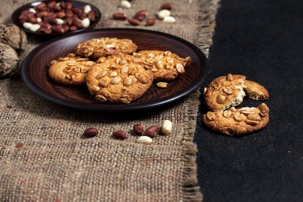 Biscotti fatti in casa di arachidi su un piatto marrone con arachidi crude