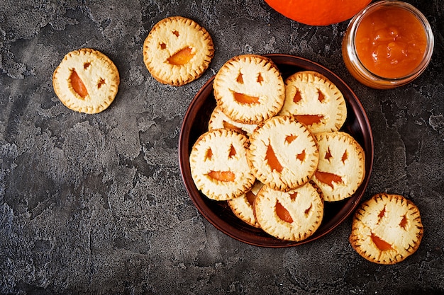 Biscotti fatti in casa in forma di zucche di Jack-o-lantern di Halloween sul tavolo scuro.