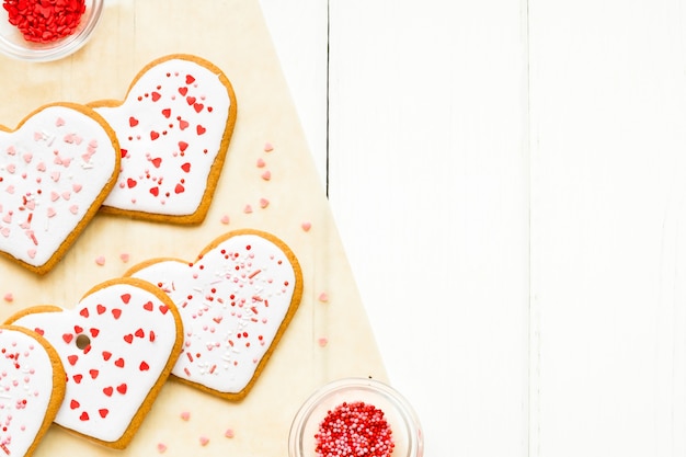 Biscotti fatti in casa per San Valentino cosparsi di cuori su sfondo chiaro