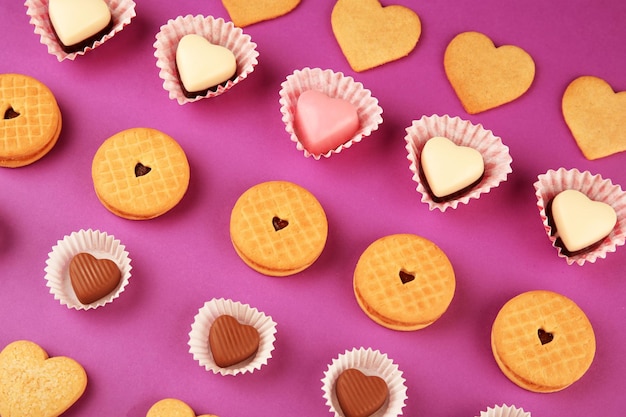 Biscotti gustosi e caramelle per San Valentino su sfondo viola