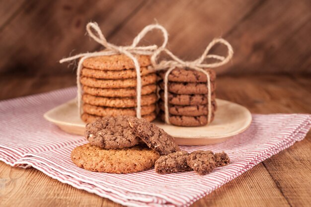 Biscotti integrali fatti in casa con farina d'avena, lino e semi di sesamo e biscotti tradizionali con scaglie di cioccolato su tavola di legno rustico scuro. Concetto di cibo vegano sano.