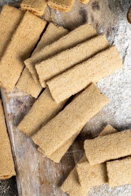 Biscotti lunghi di grano ripieni di purea di frutta diversa Biscotti con ripieno di frutta sul tavolo con farina