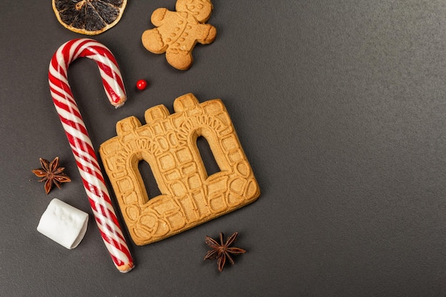 Biscotti natalizi della casa di pan di zenzero. Decorazioni tradizionali di Capodanno festivo. Sfondo in cemento di pietra nera, stile di vita, disposizione piatta, vista dall'alto