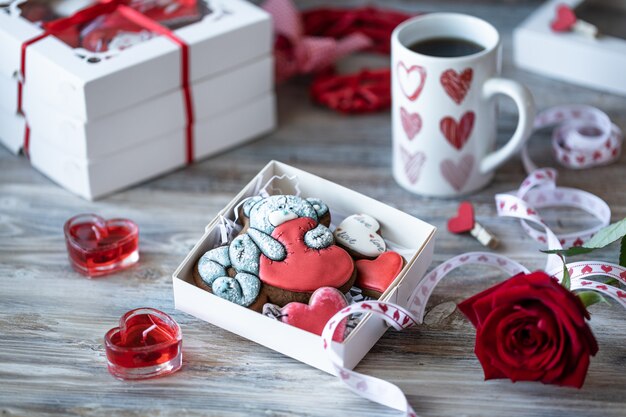 Biscotti o biscotti di pan di zenzero in un contenitore di regalo con un nastro rosso su una tavola di legno.