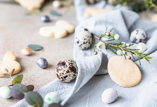 Biscotti pasquali con uova a forma di caramelle decorazioni floreali e uova di quaglia su tovagliolo di lino Concetto di vacanza