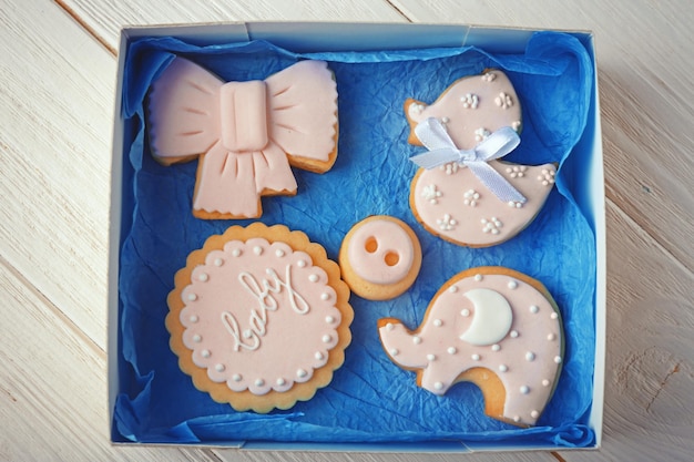 Biscotti per bambini decorati con glassa in scatola su sfondo di legno