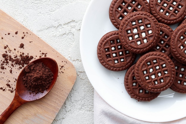 Biscotti piatti laici con cacao su un tavolo di legno bianco