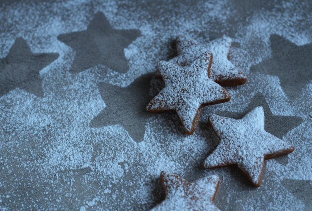 Biscotti ricci a forma di stella in zucchero a velo su sfondo grigio