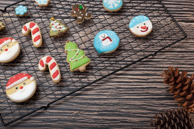 Biscotti ricoperti di zucchero e biscotti a tema natalizio su una griglia con decorazioni natalizie.