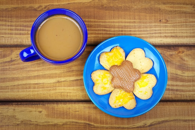 Biscotti su un piatto e una tazza di caffè sul tavolo di legno