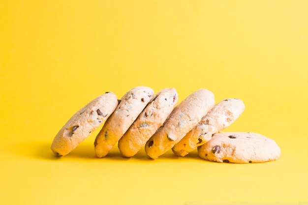 Biscotti su una superficie gialla, biscotti con pezzi di cioccolato e mirtilli rossi