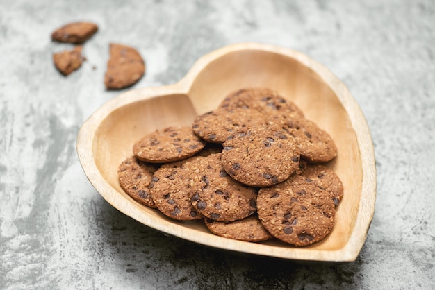 Biscotti tradizionali con gocce di cioccolato su un piatto a forma di cuore.