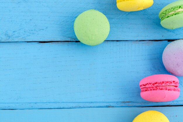 Biscotti variopinti del macaron sulla tavola d'annata di legno blu