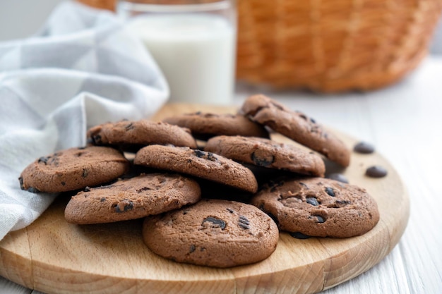 Biscotti vegani fatti in casa di cereali su tavola di legno con canovaccio e bicchiere di latte Ricetta di biscotti senza zucchero con uvetta e noci Spuntino dietetico vegano Snack o dolcetti per tè o caffè