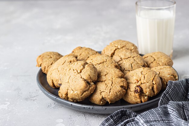 Biscotti vegani sani con noci e uvetta su un piatto di ceramica con latte