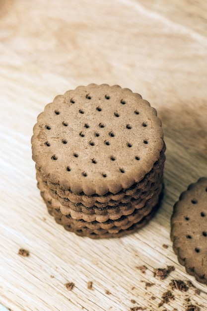 Biscotto croccante al cioccolato con fori su una tavola di legno. Biscotti rotondi ripieni