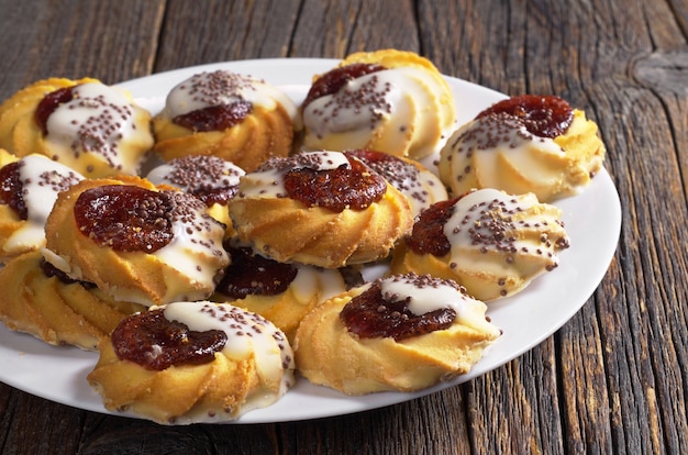 Biscotto di pasta frolla con marmellata e glassa di zucchero nel piatto sul vecchio tavolo di legno