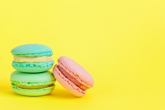 Biscotto dolce francese minimo cibo panificio concetto macaron blu e rosa su sfondo giallo