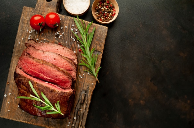 bistecca alla griglia con spezie su un tagliere, sfondo di pietra, vista dall'alto