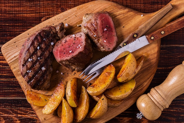 Bistecca alla griglia con spicchi di patate, salsa e spezie.