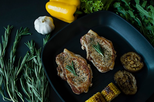 Bistecca alla griglia con verdure in padella decorata con rosmarino.