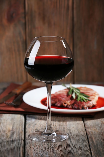 Bistecca alla griglia in salsa di vino con bicchiere di vino su fondo di legno