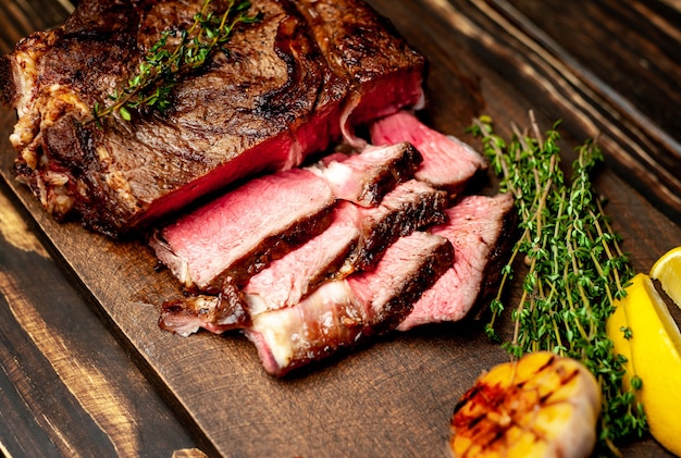 bistecca alla griglia sul tagliere con limone, peperoncino, aglio e condimento su rustico scuro