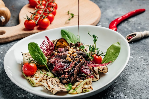 Bistecca alla griglia tradizionale affettata con insalata di verdure grigliate, noci, salsa. Sfondo di ricetta alimentare. Avvicinamento