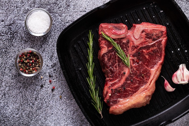 Bistecca con l'osso cruda fresca sulla padella per grigliare, vista dall'alto.