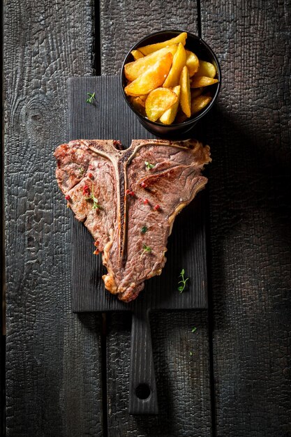 Bistecca con l'osso saporita e patatine fritte sulla roccia nera