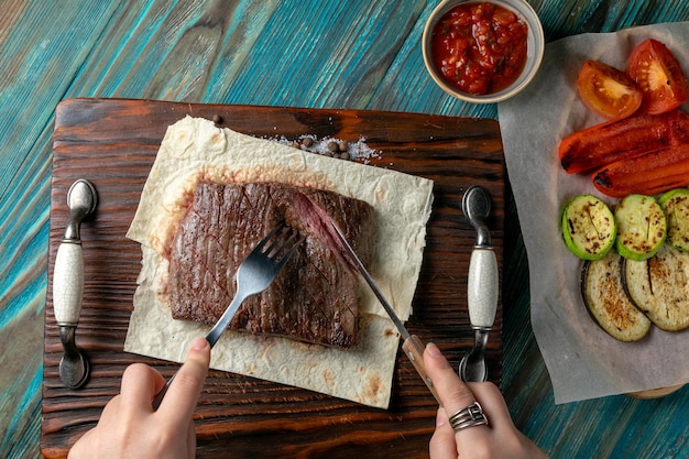 Bistecca con verdure grigliate servita su un vassoio di legno con salsa