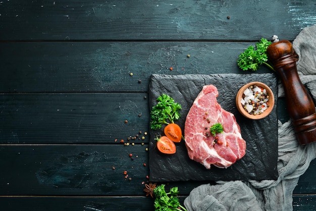 Bistecca cruda alla lavagna Carne sul vecchio tavolo con spezie ed erbe aromatiche Vista dall'alto Spazio libero per il testo