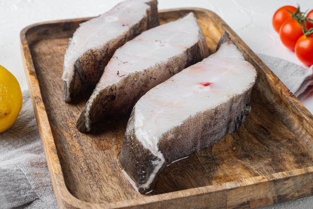 Bistecca cruda di pesce bianco, con ingredienti ed erbe aromatiche di rosmarino, su sfondo bianco tavolo in pietra