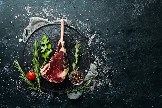 Bistecca cruda secca con osso Bistecca Tomahawk su sfondo di pietra nera Vista dall'alto Spazio libero per il testo