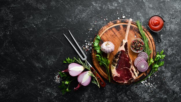 Bistecca cruda secca con osso Bistecca Tomahawk su sfondo di pietra nera Vista dall'alto Spazio libero per il testo