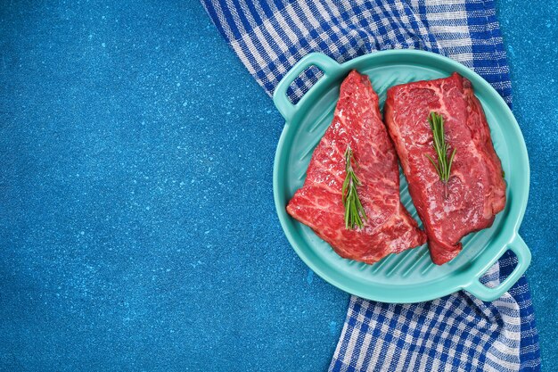 Bistecca cruda sul tagliere con rosmarino e spezie