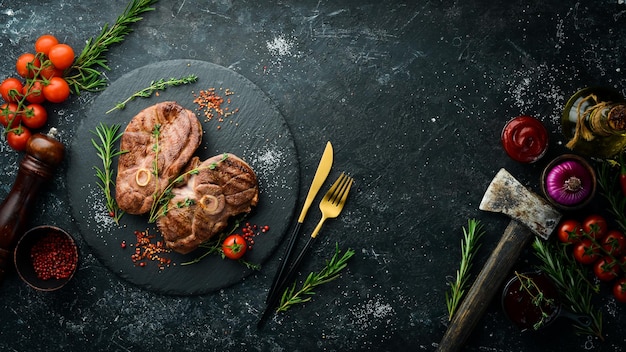 Bistecca di agnello alla griglia con spezie e rosmarino Carne al barbecue Vista dall'alto Vista piatta dall'alto su tavolo da taglio in pietra nera