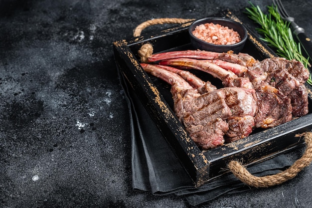 Bistecca di agnello alla griglia cotoletta di carne di montone in vassoio di legno Sfondo nero Vista dall'alto Spazio di copia