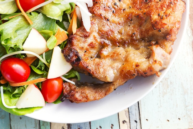 Bistecca di braciola di maiale al pepe nero con insalata.