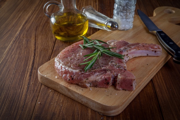 bistecca di braciola di maiale cruda su fondo di legno.