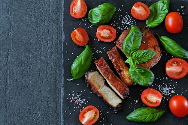 Bistecca di carne appetitosa fresca su una tavola con pomodori e basilico.