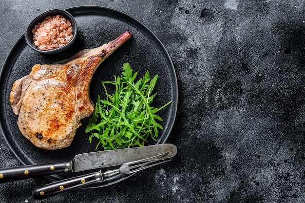 Bistecca di carne di braciola di maiale tomahawk alla griglia barbecue su una tavola di marmo