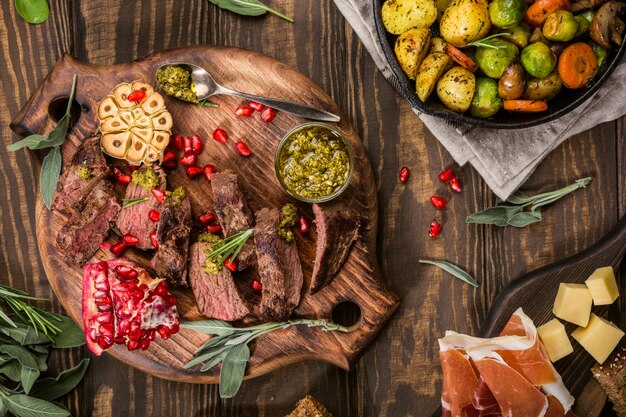 Bistecca di carne di canguro con pesto verde e melograno sul tagliere di legno.