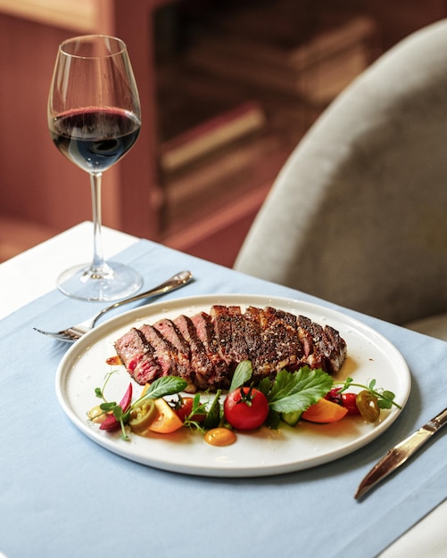 Bistecca di carne di manzo arrosto con bicchiere di vino rosso