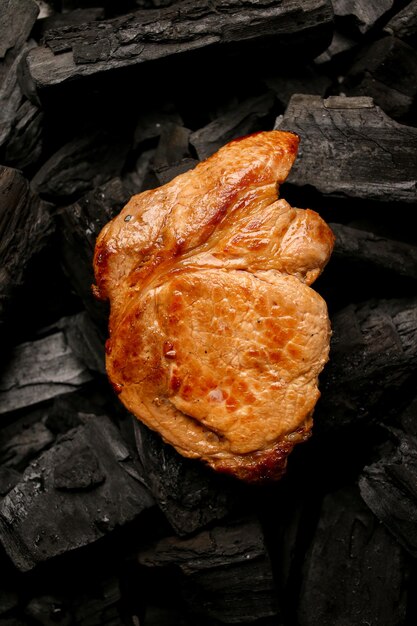 Bistecca di carne fritta su uno sfondo nero di carbone Bistecca succosa cotta alla brace