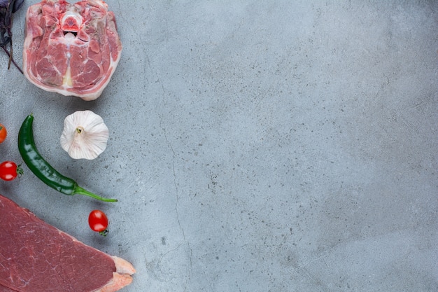 Bistecca di carne rossa cruda e verdure sul tavolo di pietra.