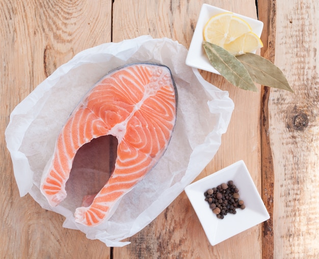 Bistecca di color salmone crudo pesce rosso e spezie sul tavolo di legno