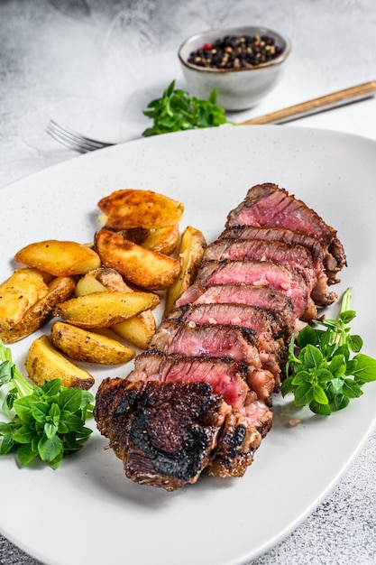 Bistecca di controfiletto a fette con patate. Sfondo bianco. Vista dall'alto.