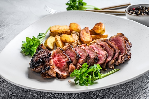 Bistecca di controfiletto a fette con patate. Sfondo bianco. Vista dall'alto.