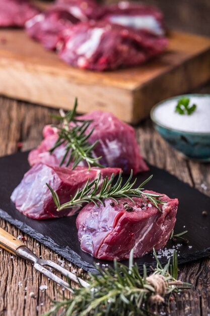 Bistecca di filetto di manzo crudo su tagliere con sale pepe rosmarino in altre posizioni